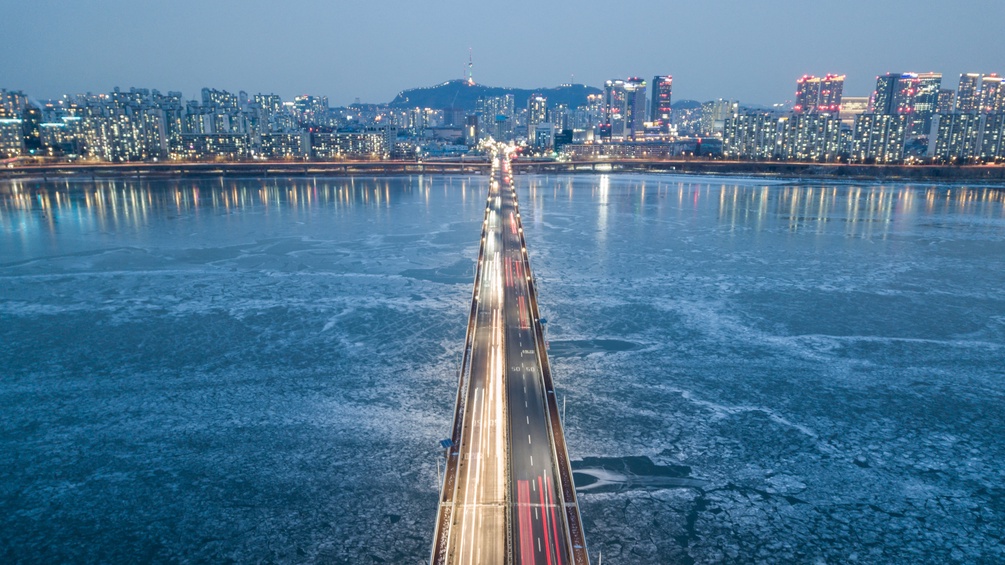 Verkehr auf Brücke über den Han-Fluss, im Hintergrund Skyline von Seoul