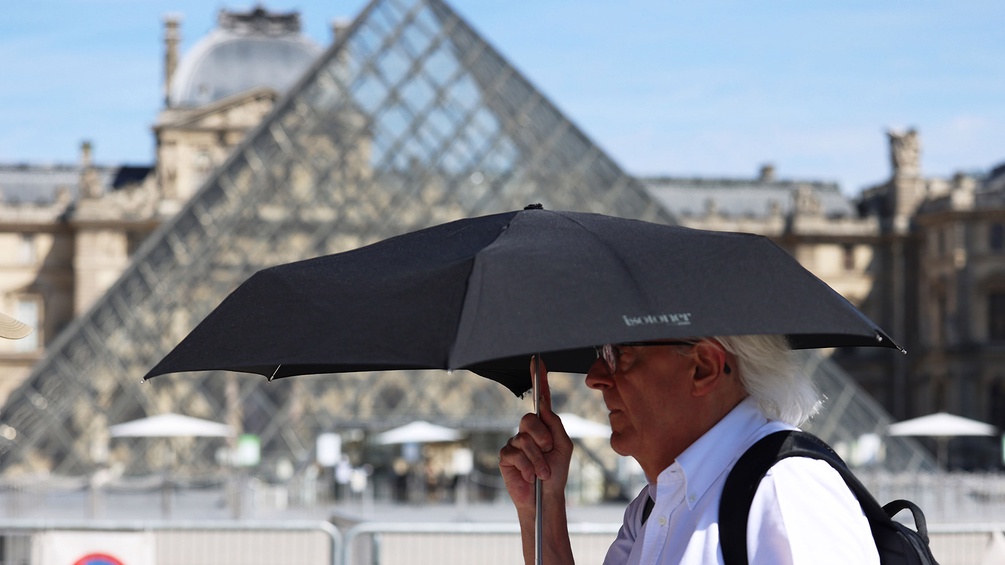Mann mit Schirm vor dem Louvre, Paris