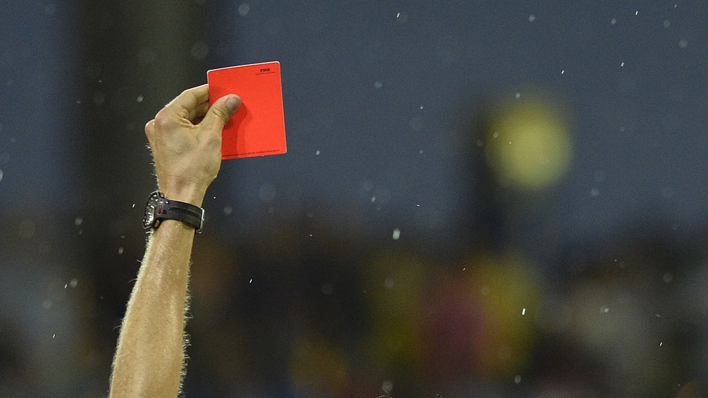 Die Hand eines Schiedsrichters, die gerade eine Rote Karte zeigt.