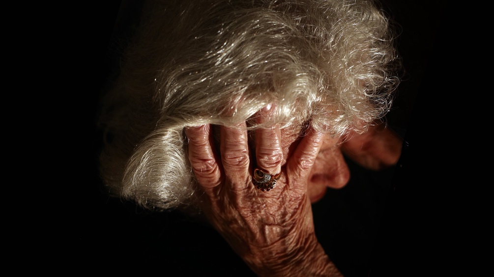 Eine ältere Frau greift sich an den Kopf
