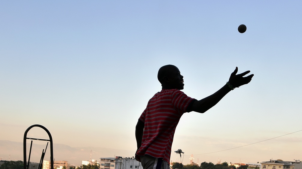 Junger Mann spielt Ball in Haiti, Abendsonne