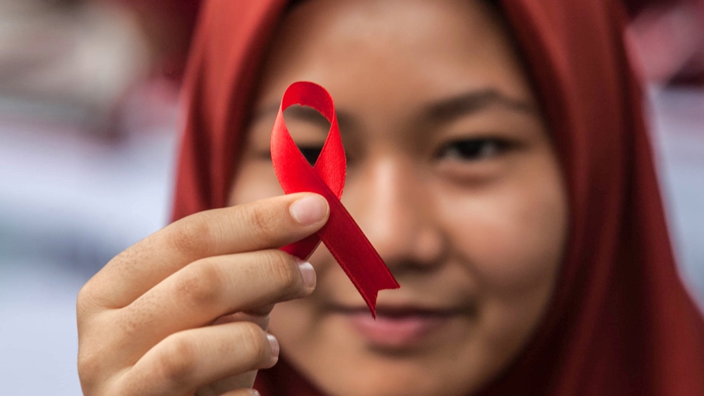 Indonesisches Mädchen hält eine Aids Schleife in der Hand