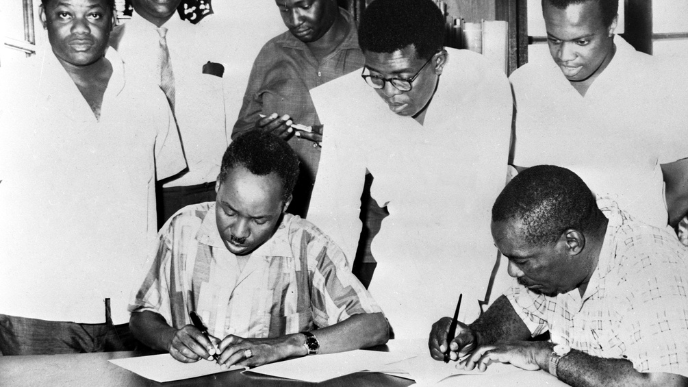 Das Foto zeigt, wie der tangaikische Außenminister Oscar Kambona, Präsident Julius Nyerere, Zanzibars Vizepräsident Kassim Hanga (mit Brille) und Zanzibars Präsident Abeid Karume am 22. April 1964 die Vereinbarung zur Vereinigung ihrer Länder unterzeichneten.