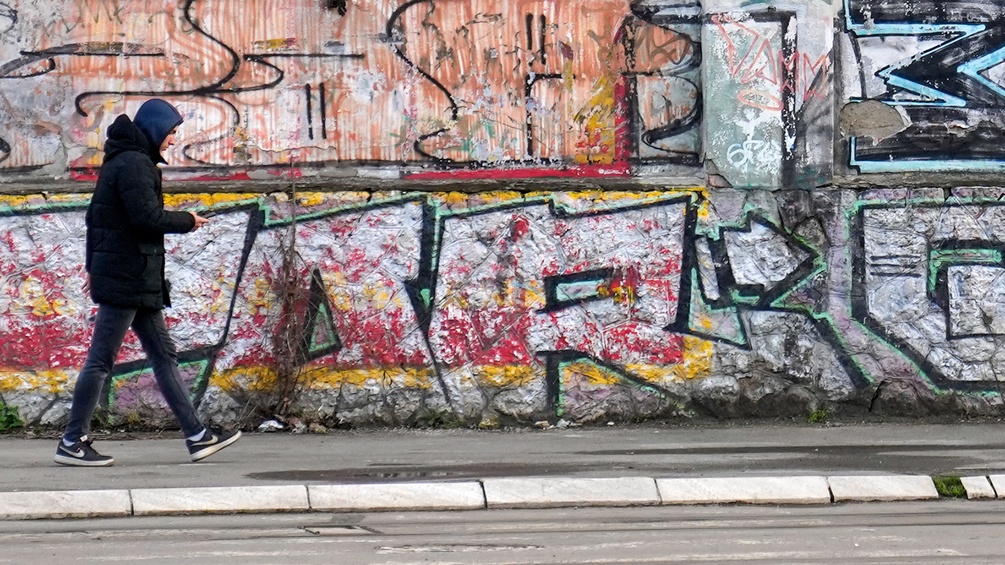 Junger Mann vor Graffitis in Serbien