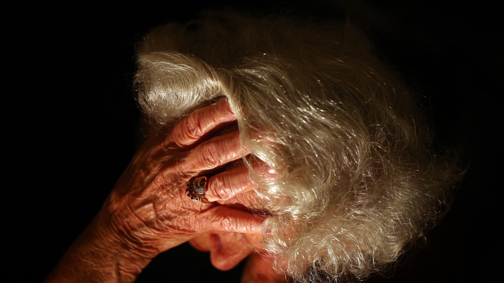 Eine ältere Frau hält sich die Hand vor das Gesicht