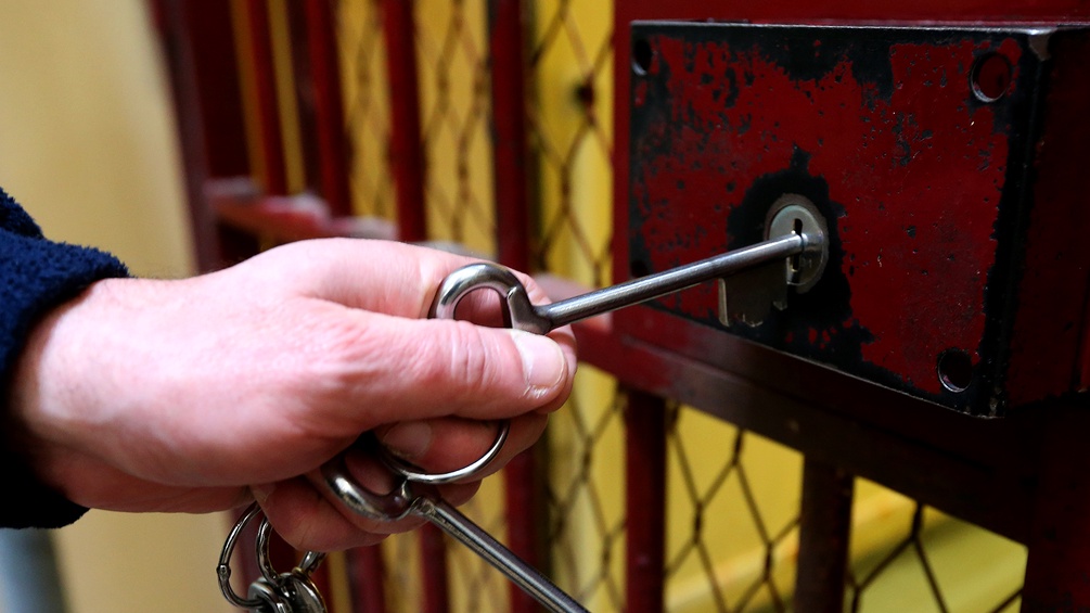 Männerhand mit Schlüssel schließt eine Türe auf
