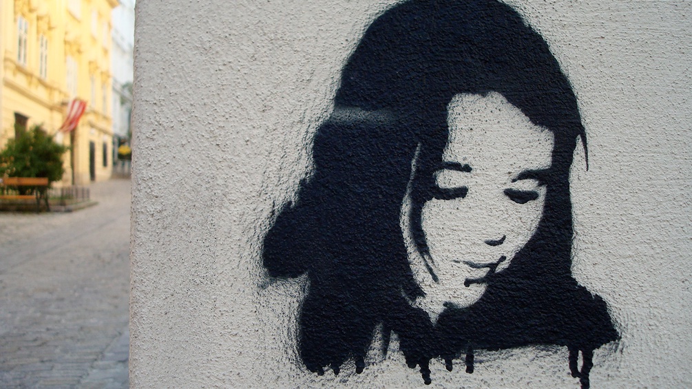 Graffiti eines jungen Mädchens an einer weißen Hauswand