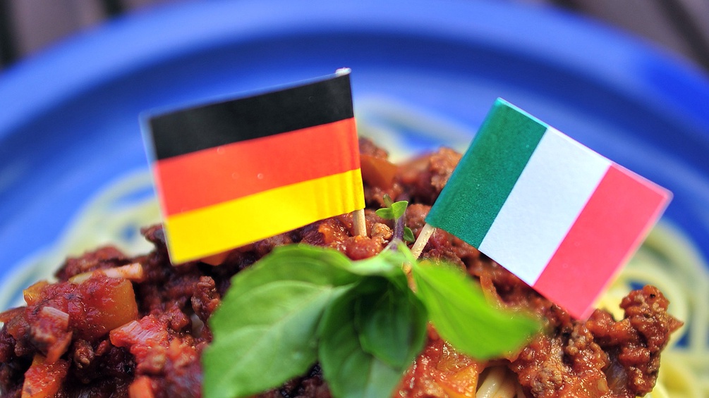Eine deutsche und eine italiensiche Fahen auf einer Portion Spaghetti