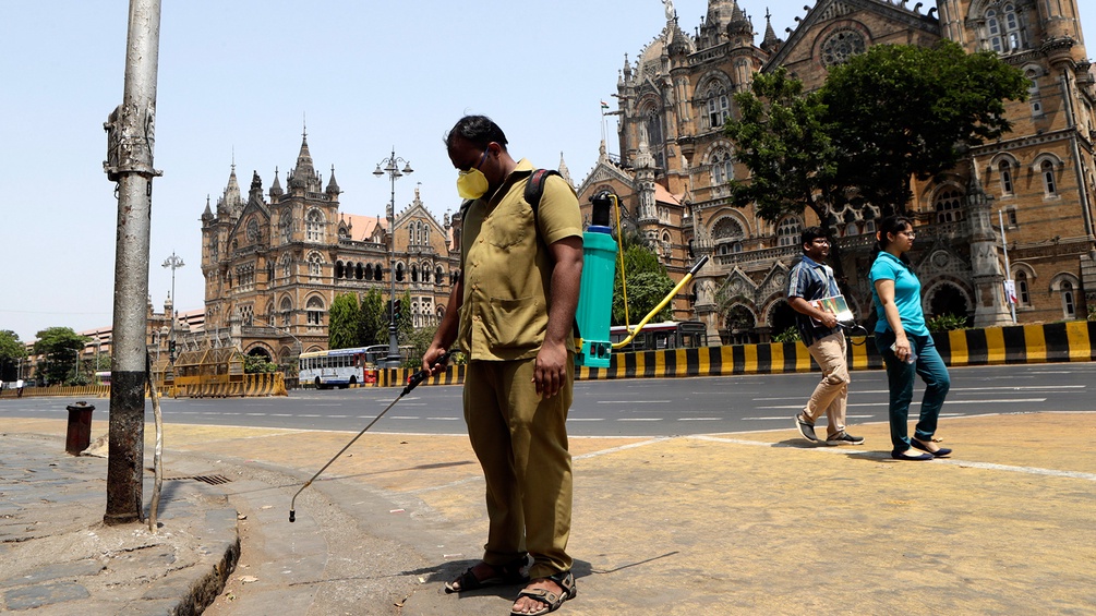 AP/RAJANISH KAKADE Mann in Mumbai mit Mundschutz auf offener Straße mit Desinfektionsmittel
