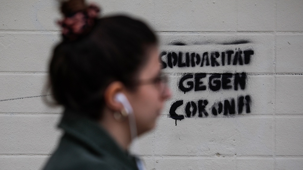 Eine Frau geht an einem Slogan vorbei der heisst:" Solidarität gegen Corona".