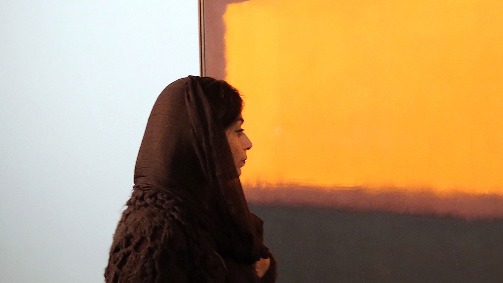 Eine Iranerin betrachtet das Gemälde eines iranischen Künstlers
