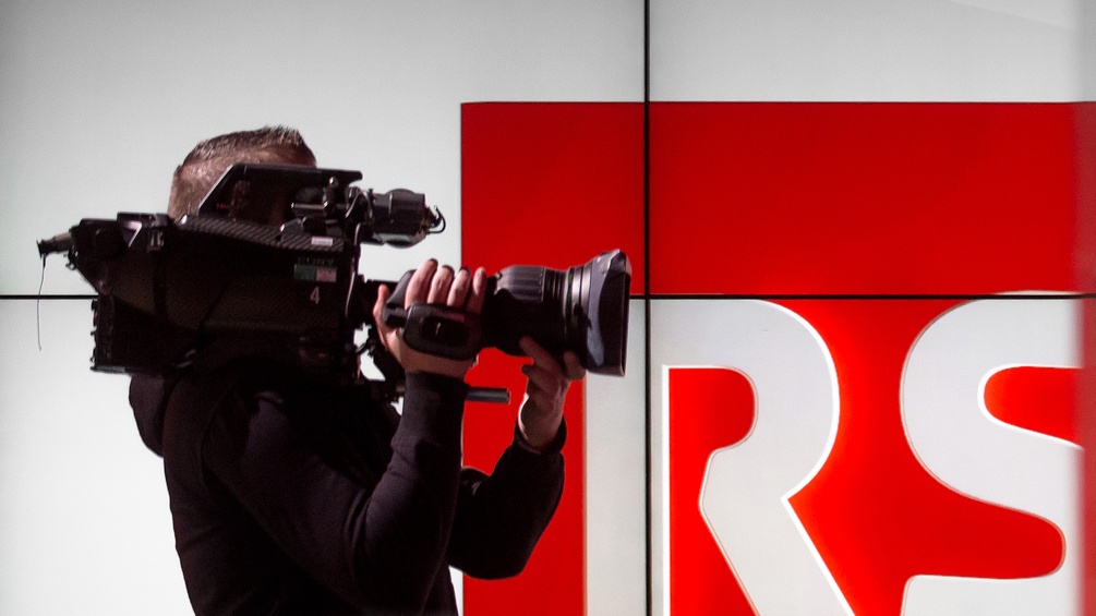 Ein Kameramann steht vor dem Logo des Schweizer Senders "Radiotelevisione Svizzera".