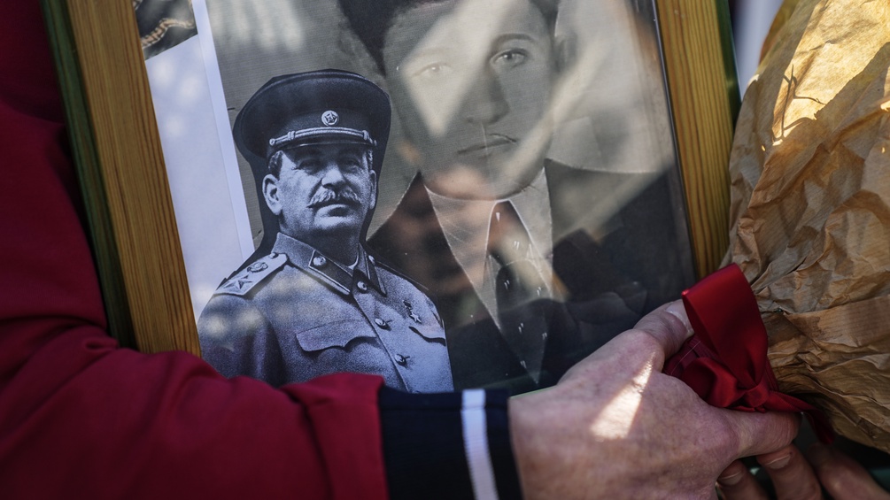 Eine Frau hält ein Familienfoto und ein Bild von Stalin