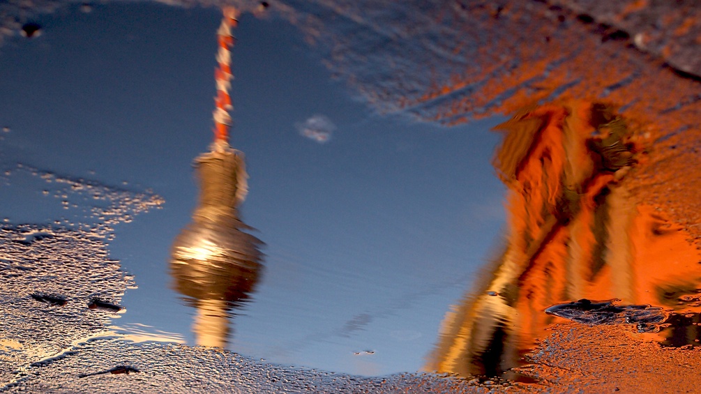 Der Berliner Fernsehturm spiegelt sich in einer Wasserlache