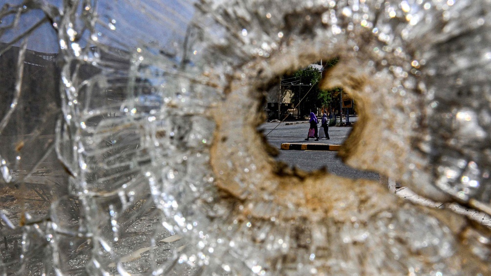 Zerstörtes Glas, dahinter Blick auf zwei Frauen im Sudan