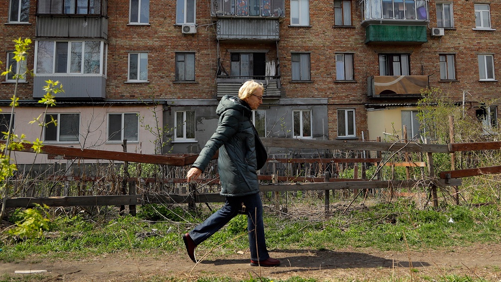 Eine Frau geht vor einer Kiewer Wohnhauszeile