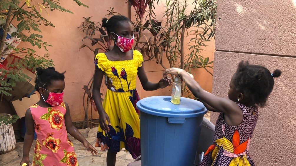 Mädchen mit Mundschutz waschen sich die Hände, Senegal
