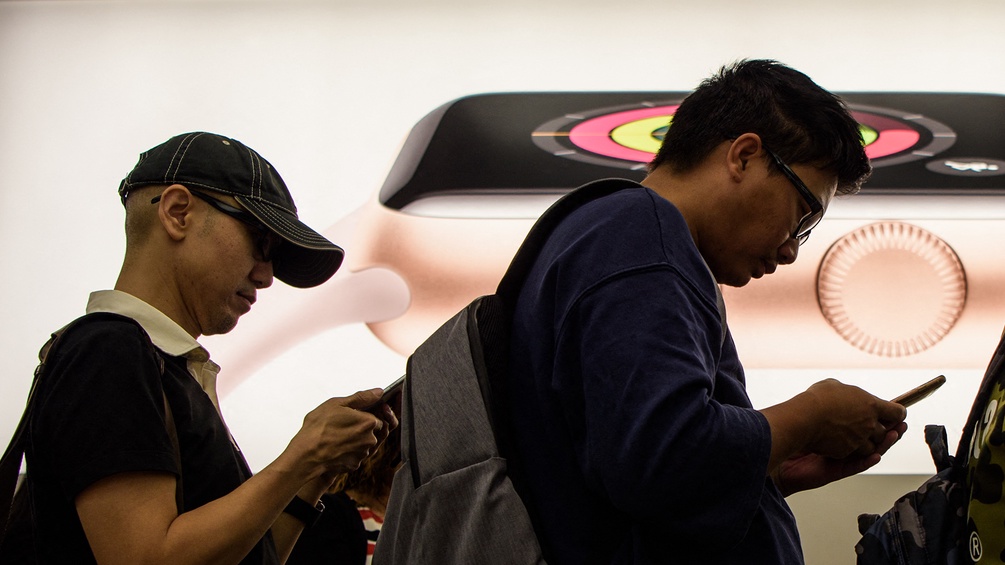 Kunden vor dem Apple Store starren in ihre iPhones.