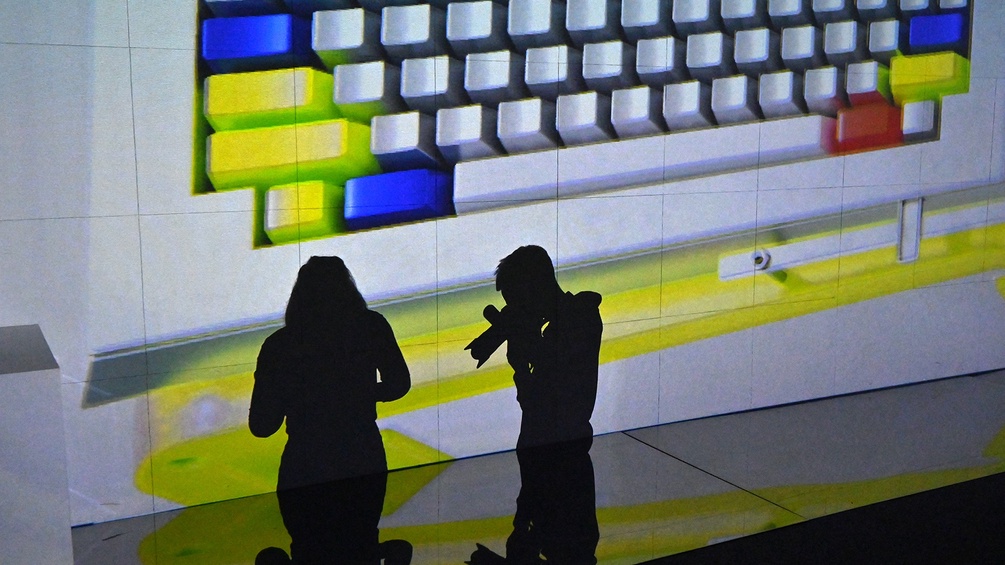 Zwei Besucher der Biennale in Kiev stehen vor einer Projektion eines riesigen Keyboards.