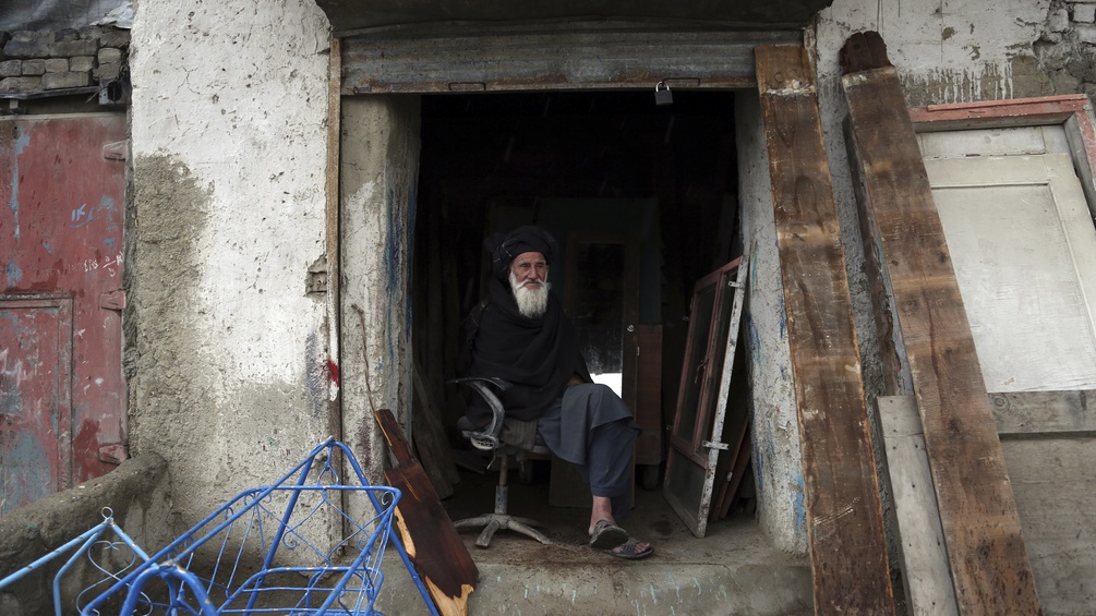 Ein alter Teppichmann in Afghanistan sitzt in seiner Türe