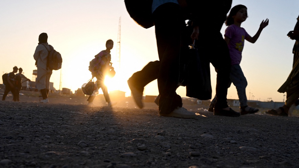 Menschen auf der Flucht bei einem Grenzübergang, Sonnenuntergang