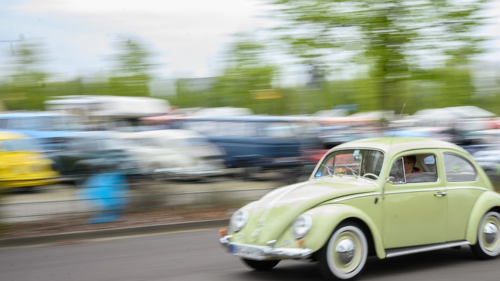 Ein Volkswagen Käfer fährt auf einem Parkplatz der Messe Hannover.