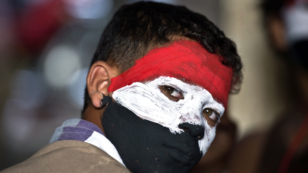 Ein Demonstrant. Das Gesicht mit den Nationalfarben Ägyptens bemalt