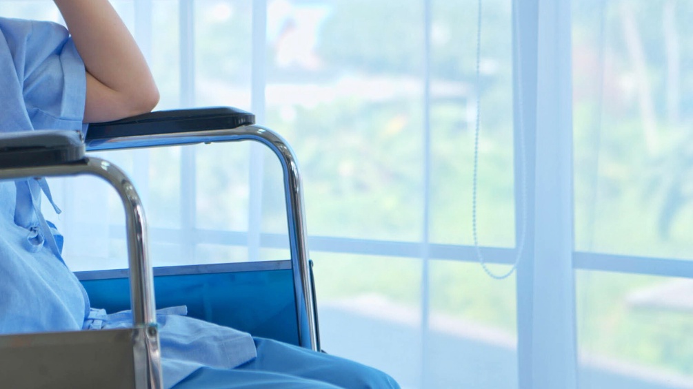Dame in einem Rollstuhl in einem Krankenhaus am Fenster