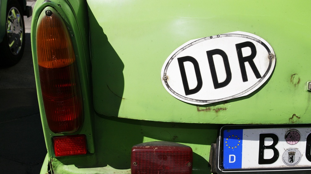 Ein Trabant-Fahrer benutzt das DDR - Nationalitaetskennzeichen neben dem Berliner Nummernschild
