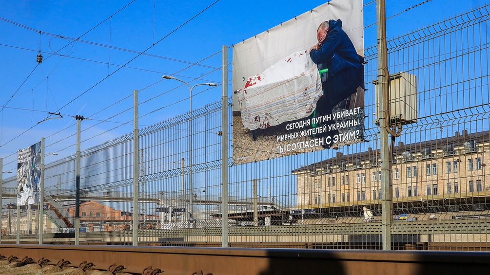 Schockierende Bilder sind an den Zäunen neben den Bahngleisen in Vilnius aufgehängt.