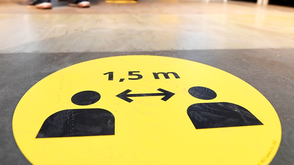 Ein Icon am Boden, das 1,5 Meter Abstand zwischen zwei Personen anzeigt