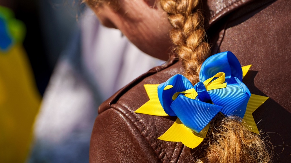 Junges Mädchen mit Zopf und Masche in den Farben der Ukraine