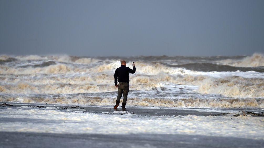 Mann am Strand mit Smartphone in der Hand
