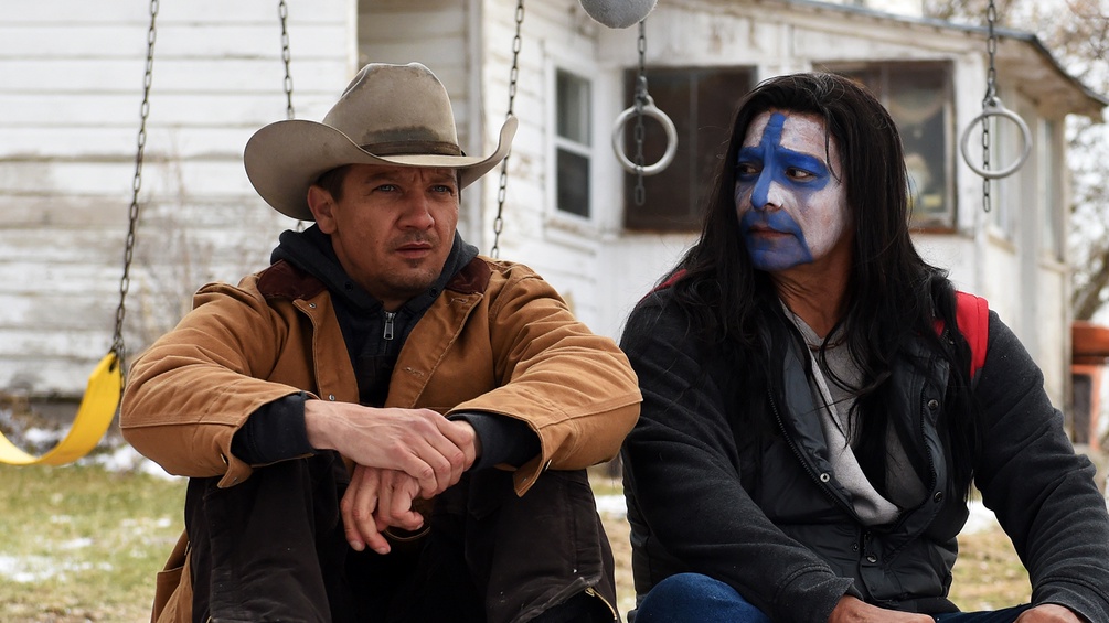  Jeremy Renner mit Cowboyhut und Indianer mit Gesichtsbemalung