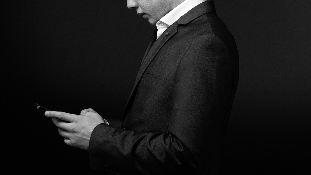 Ein junger Mann in Anzug am Handy.