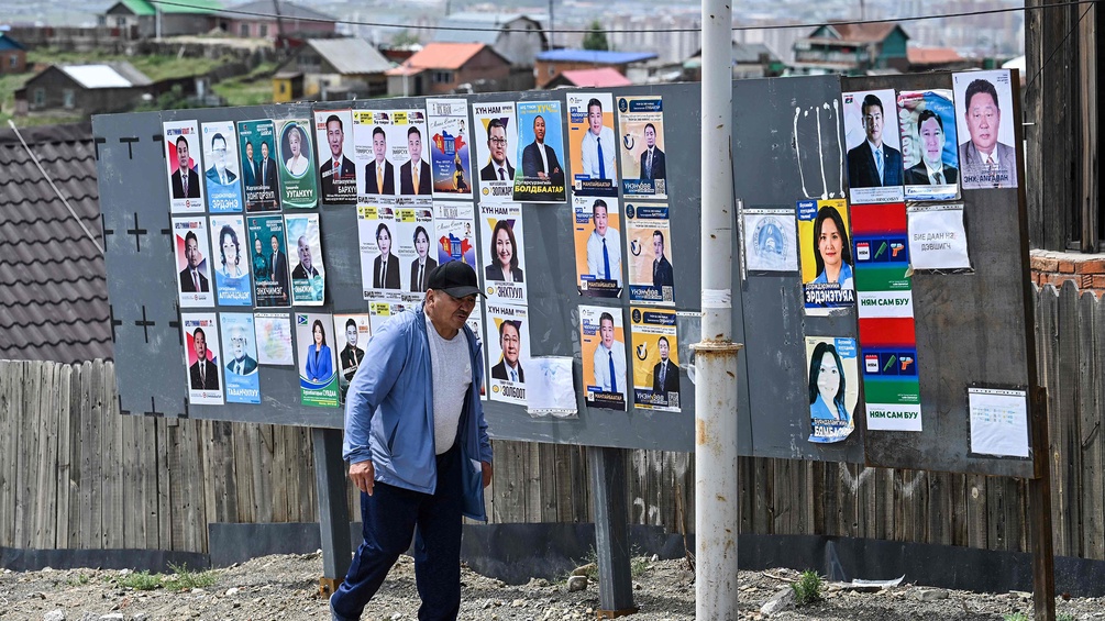 Mann geht an unterschiedlichen Wahlplakaten in der Mongolei vorbei