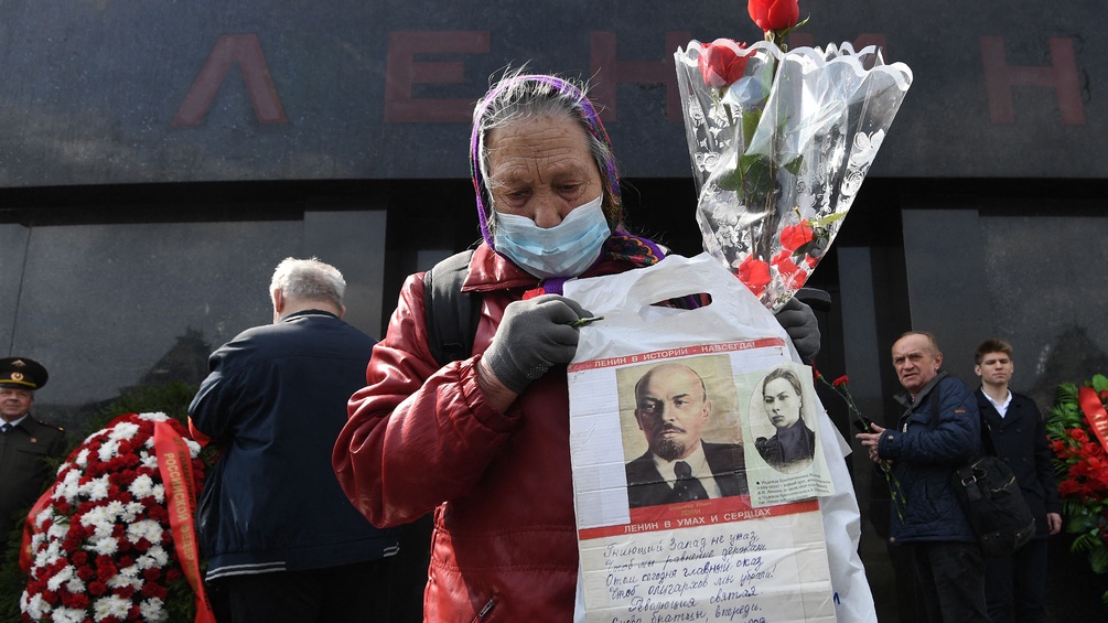Eine Frau mit einem Bild von Lenin vor seinem Mausoleum