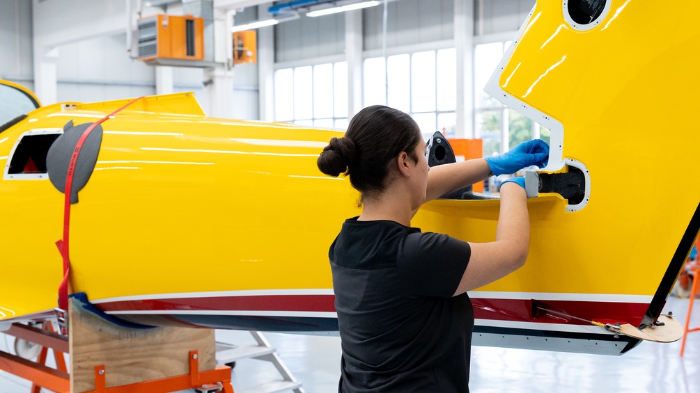 Eine weibliche Fachkraft montiert in einer Industriehalle etwas