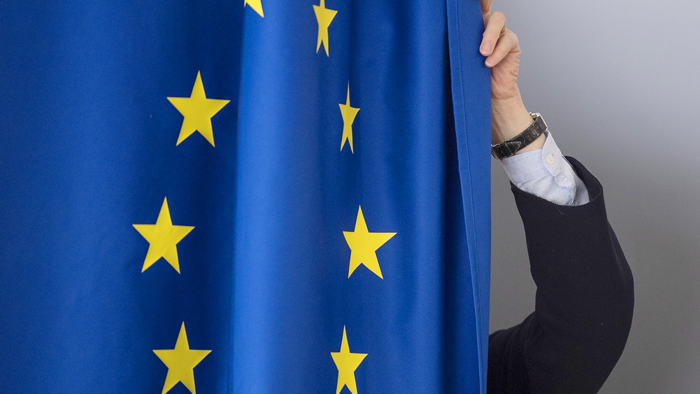 Eine Wahlkabine mit einer Europaflagge als Vorhang 
