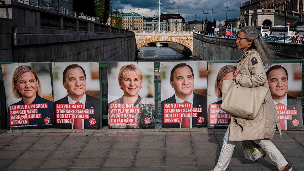 Eine Frau geht in Stockholm an Wahlplakaten vorbei