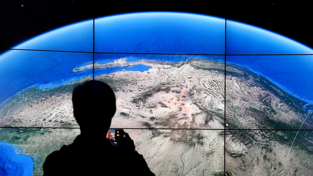 Ein Mann steht vor einem Bildschirm von Google Earth.