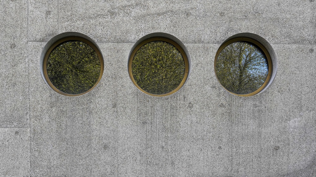 Drei gleiche, runde Fenster in einer Betonwand