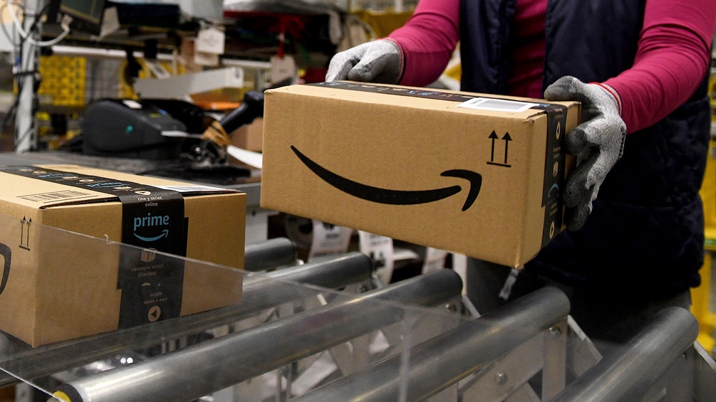 Frau arbeitet bei Amazon am Fließband, hält Paket in Händen
