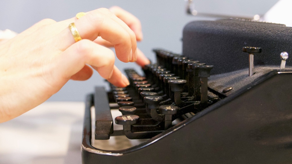 Frau tippt auf einer Schreibmaschine