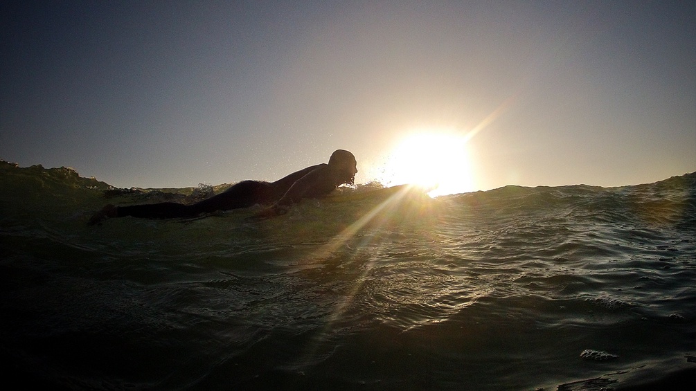 Ein Mann liegt auf einem Surfbrett im Wasser