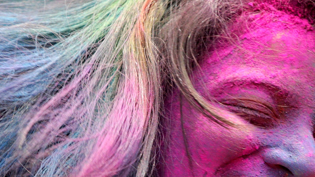 Frau mit purpurfarbenen Gesicht während eines Holi-Festes