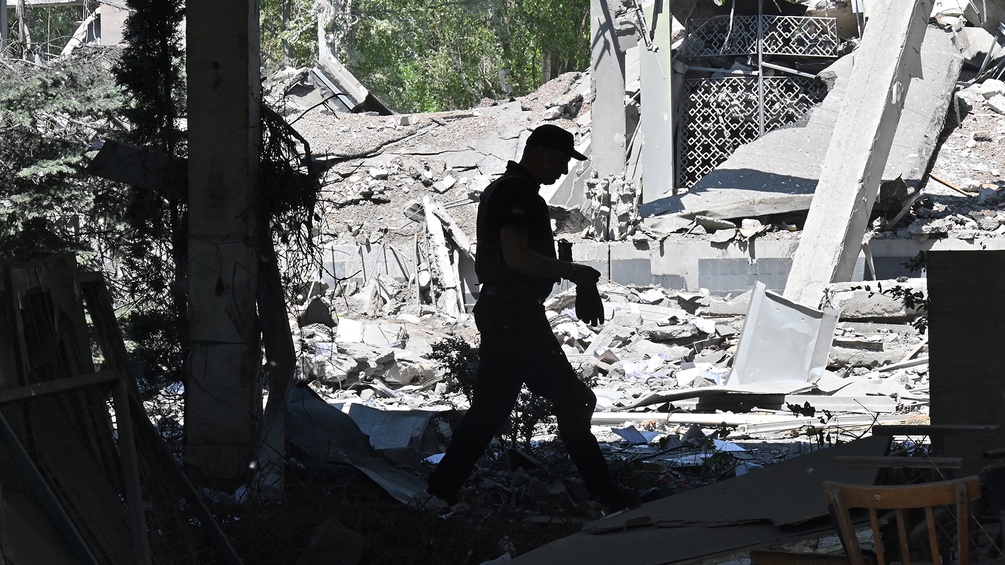 Ein Mann streicht durch Trümmer von Häusern in der Ukraine.