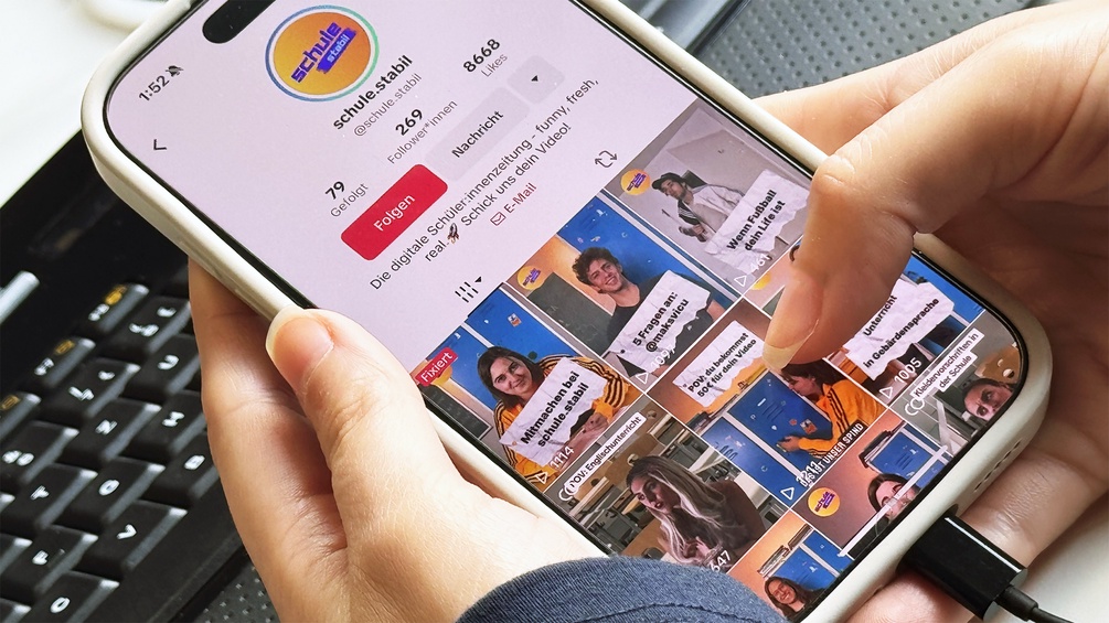 Kollegin Lara hält ein Handy und zeigt "schule stabil" auf TikTok