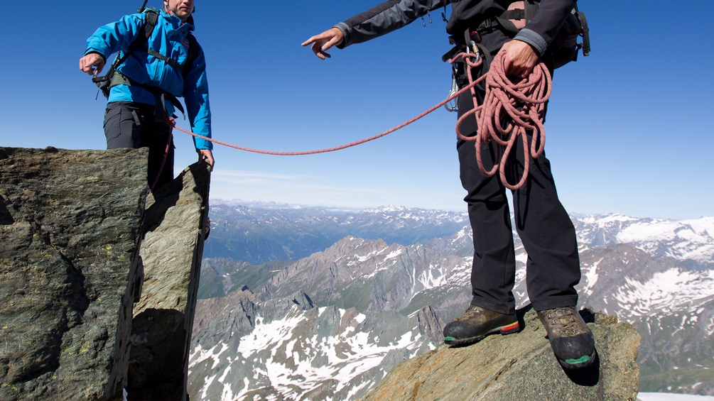 Ein Bergführer sichert einen Bergsteiger am Seil 