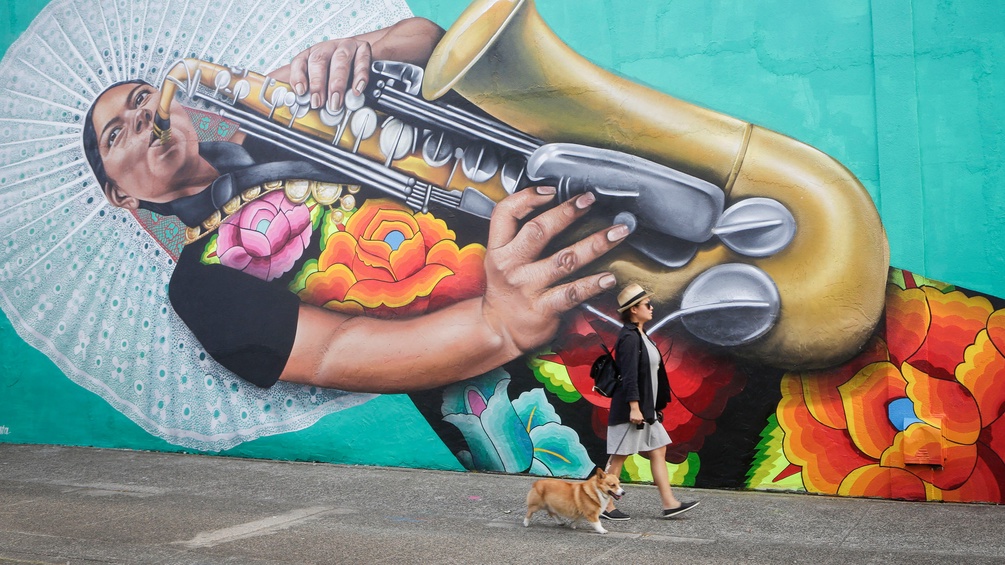 Großes Mural in Vancouver, davor spaziert eine Frau mit einem Corgi vorbei